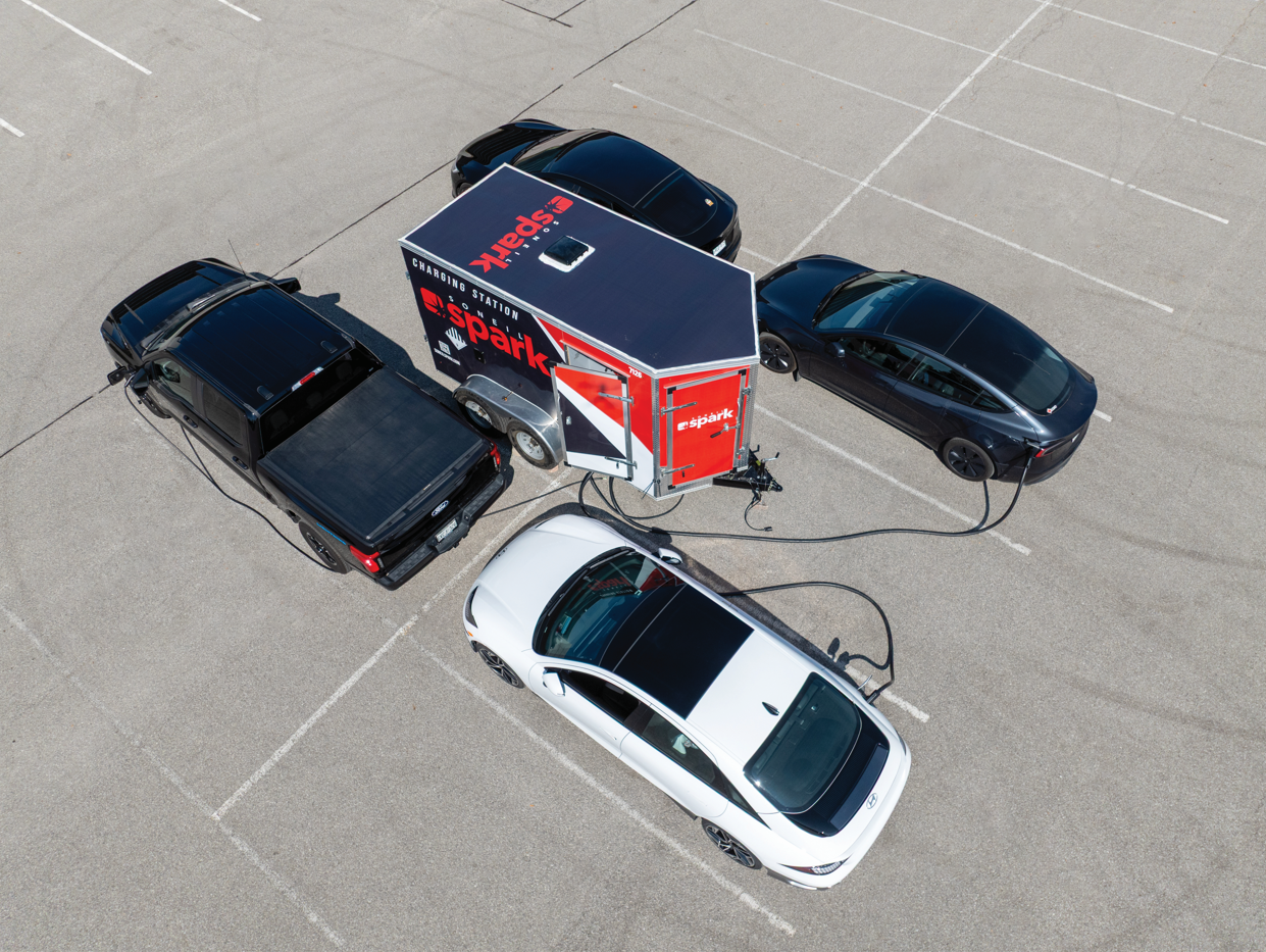 Four EVs charging at once from the Spark Mobile Charging Trailer in a parking lot